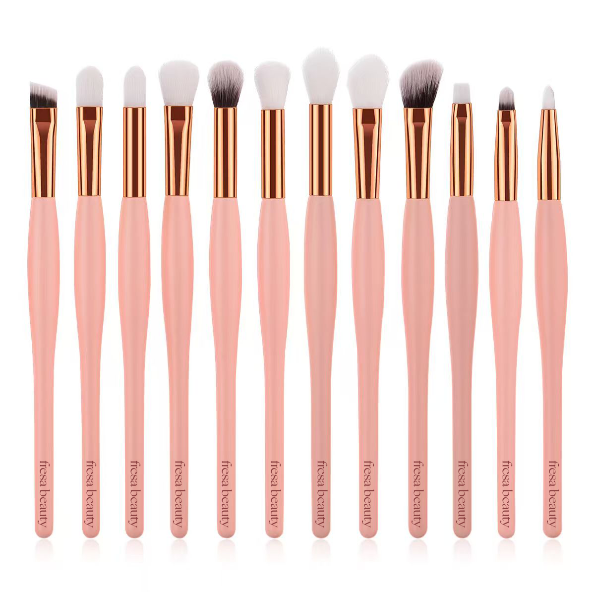 A 12-piece makeup brush set with pale pink handles, rose gold ferrules, and white bristles, arranged in a row against a white background.
