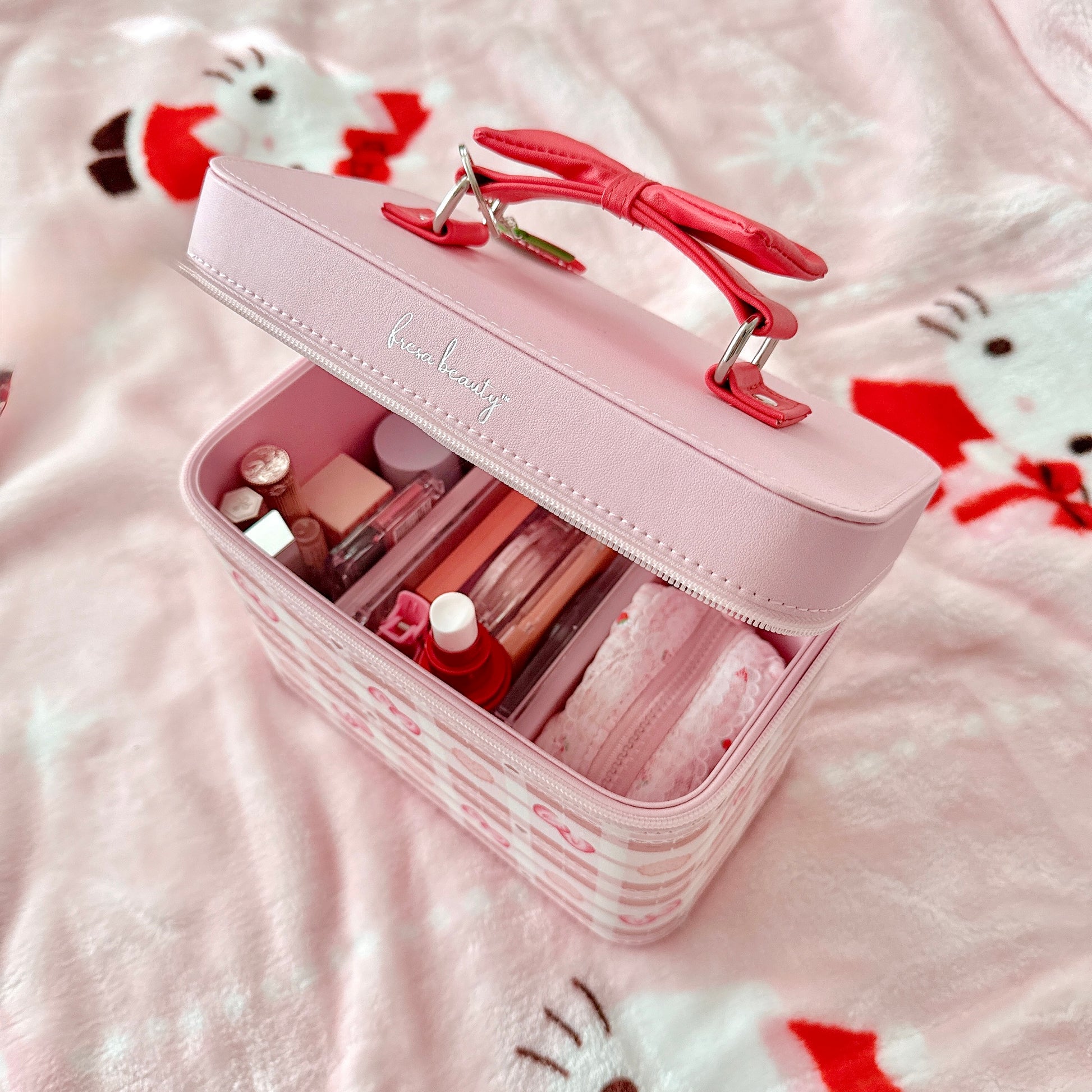 Pink makeup case with cosmetic items on a soft surface