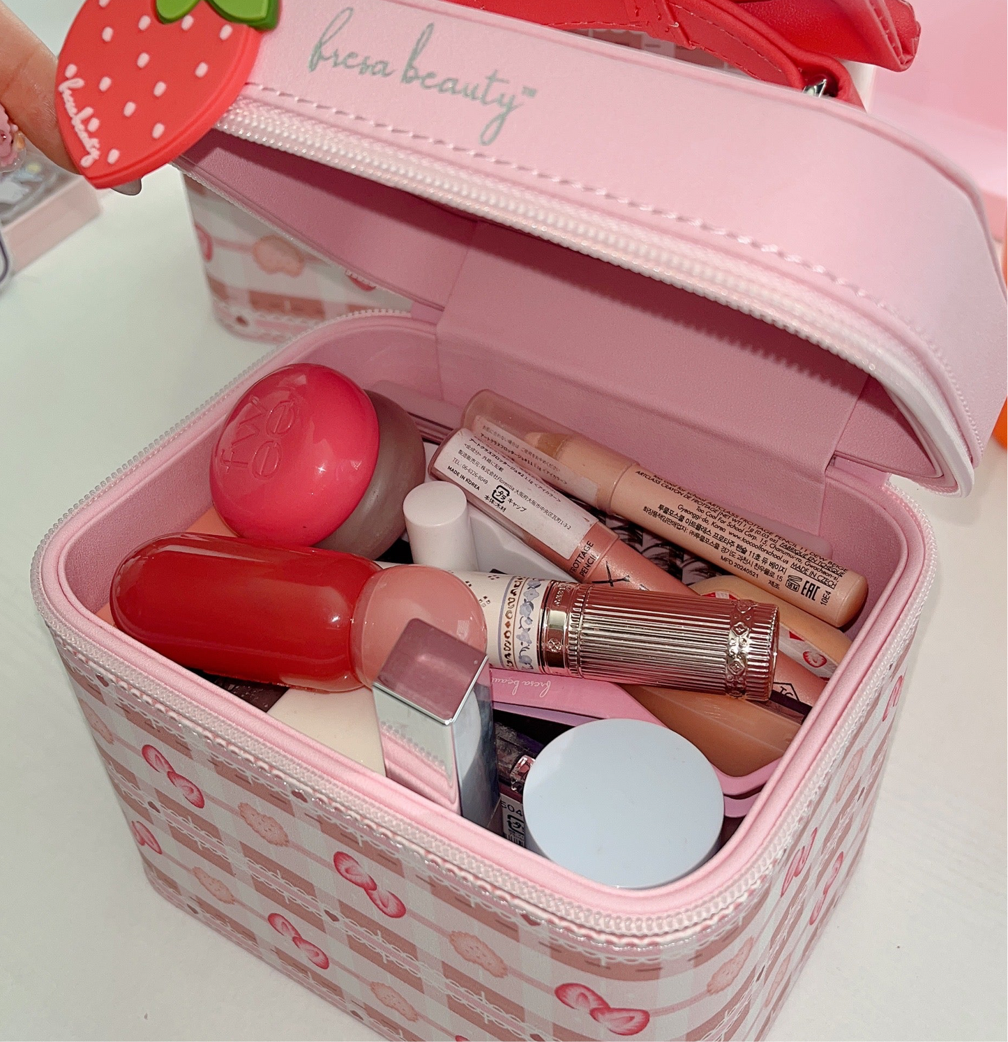 Pink makeup case with cosmetic products on a white background