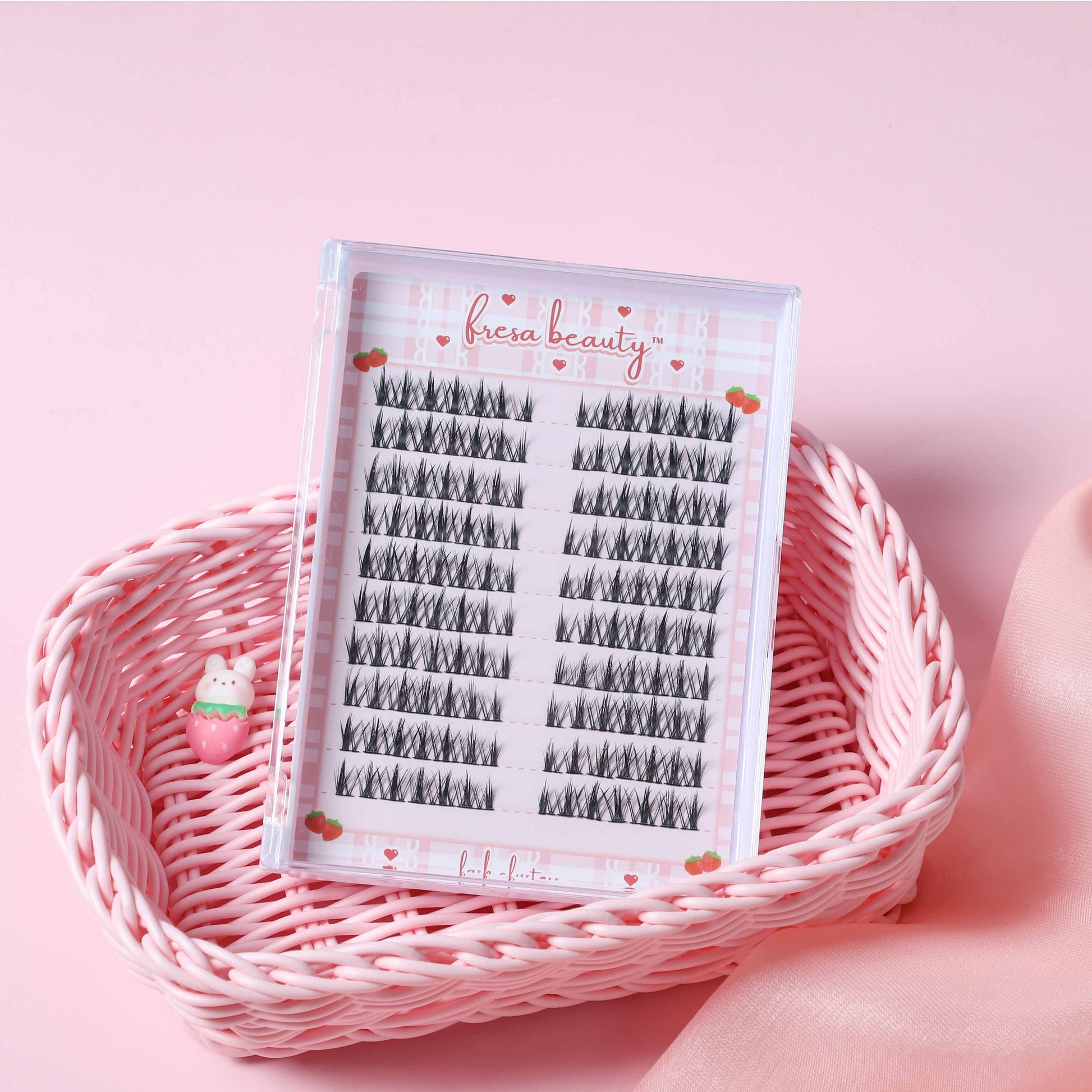 Faux eyelashes in a clear plastic case on a pink background