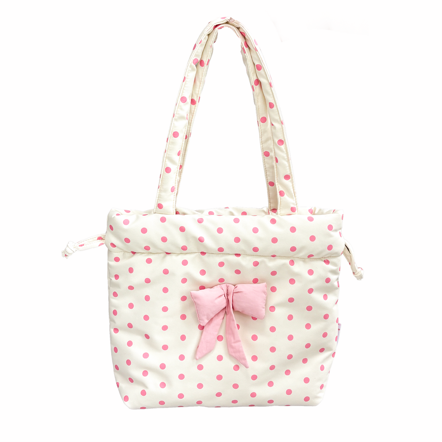 A cream yellow-colored padded tote bag with pink polka dots, featuring a matching pink fabric bow on the front and dual shoulder straps, set against a plain white background.